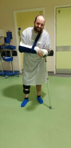 Kieran in hospital with a crutch and arm sling