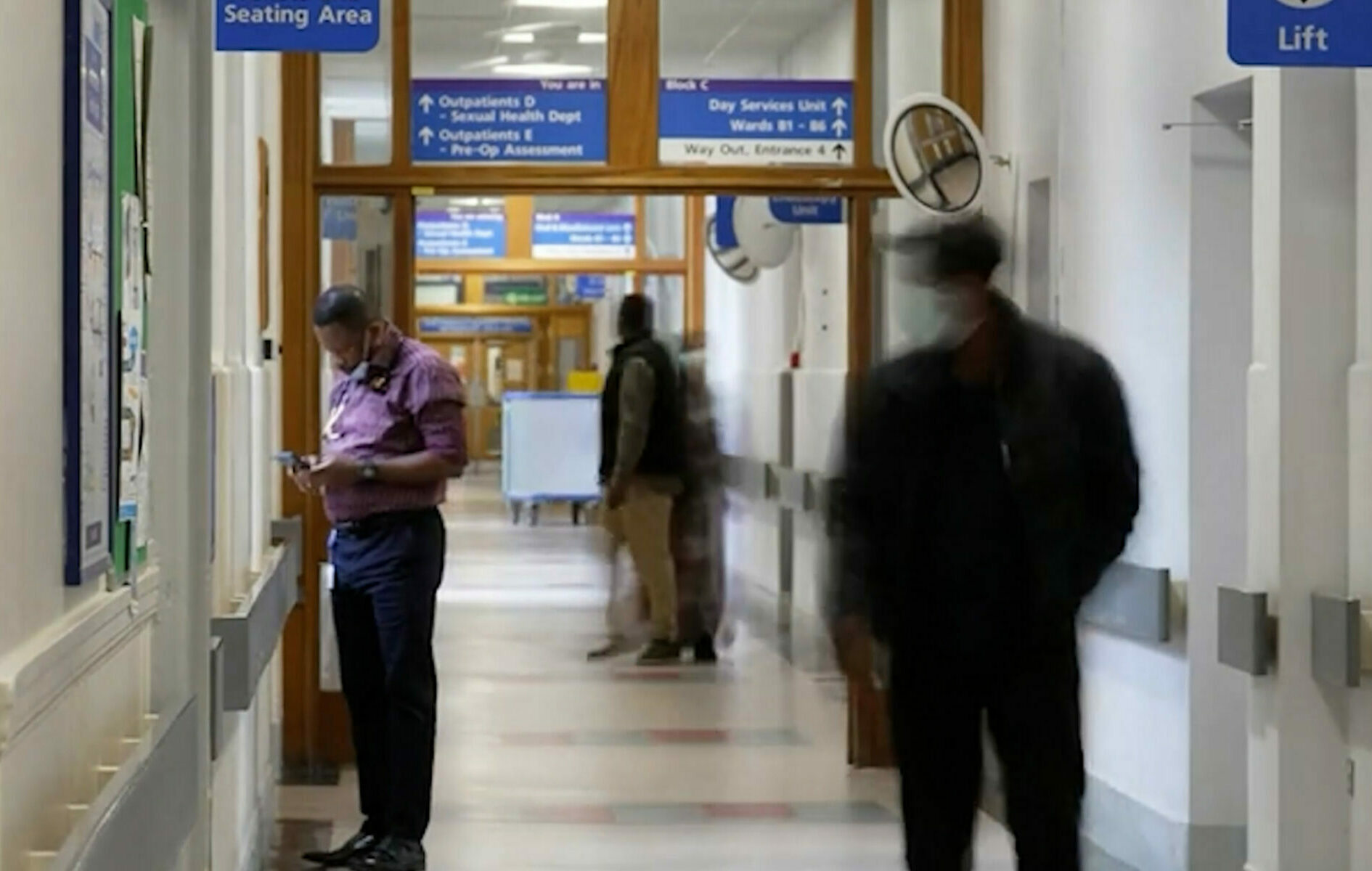 Hospital corridor with people walking down it