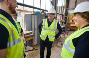 Andy Burnham wearing a hard hat and hi-vis jacket smiling