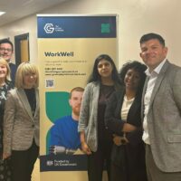 Six people stood in hospital corridor with WorkWell sign