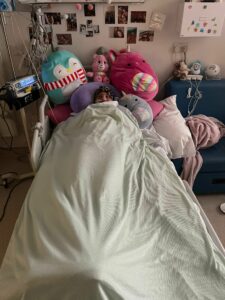 Girl in hospital bed surrounded by toys