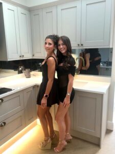 Two women in black dresses posing in a kitchen