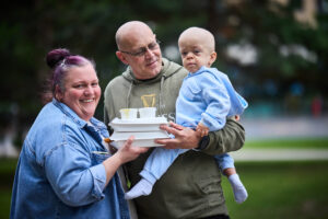 A man and a woman holding their child and takeaway boxes