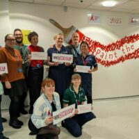 A group of people stood next to a World AIDS day mural