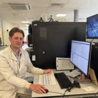 Man in lab coat working at computer.