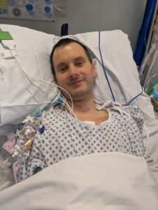 Man in hospital bed attached to lots of wires.