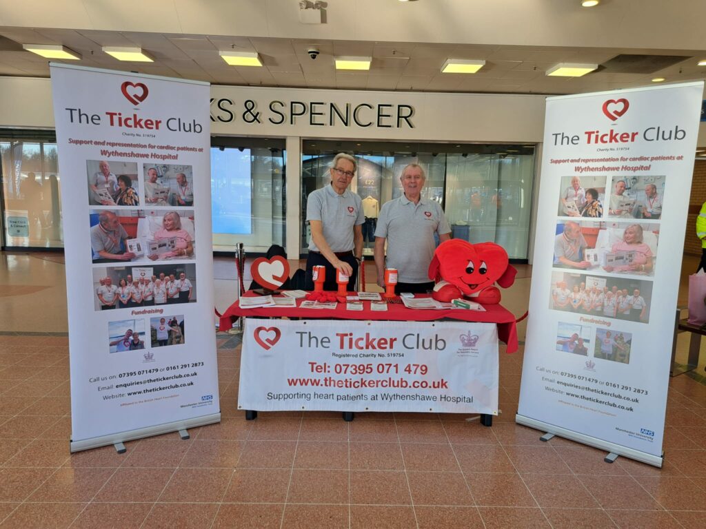 Handforth Dean 4 Two men stood behind a The Ticker Club table.