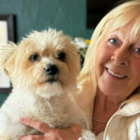 Woman holding dog and smiling.