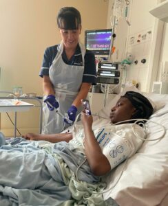 Nurse giving treatment to patient laying in bed.