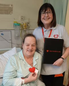 Volunteer stood with a patient in bed.