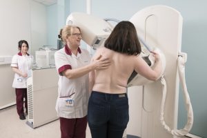Female nurse assisting a female patient undergoing mammogram breast screening