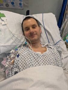 Man in hospital bed attached to lots of wires.