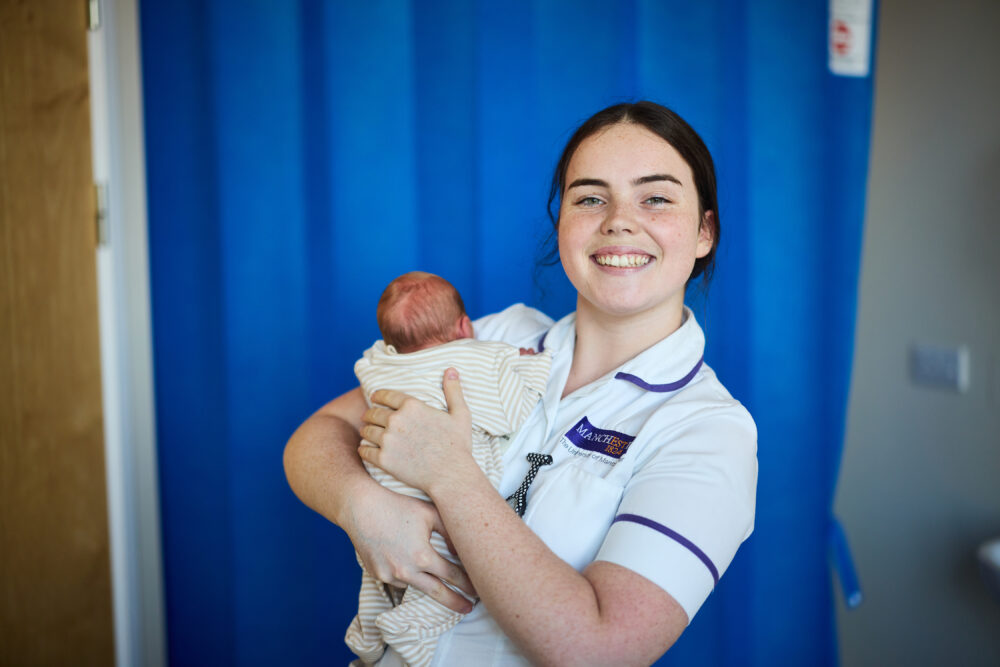 Student midwife holding baby.