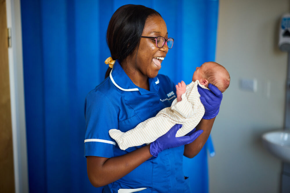 Midwife smiling at baby.