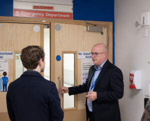 Man opening the door to Emergency Department to another man